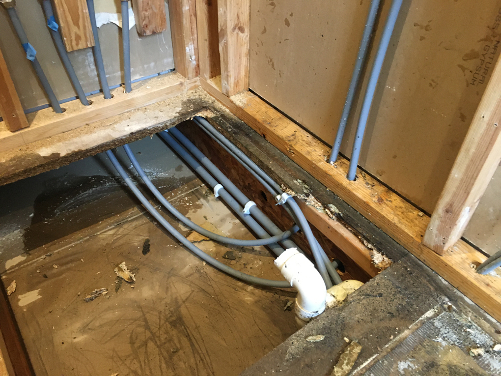 Stripped ensuite shower room showing wet areas from water pipe leaks