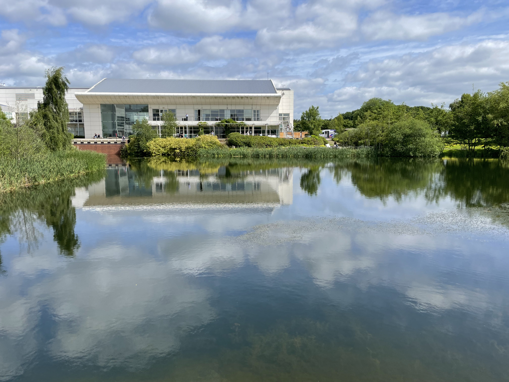 Picture of lake with two storey building in background on a sunny day