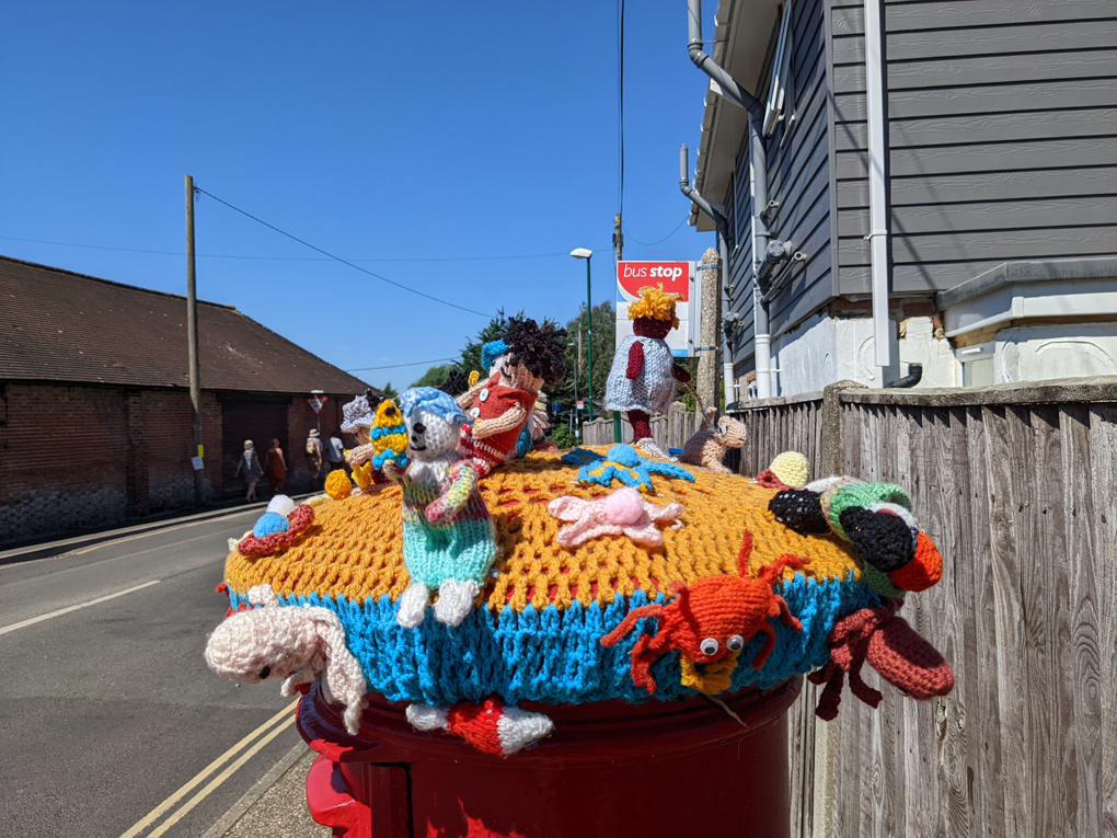A postbox with a knitted beach scene on top