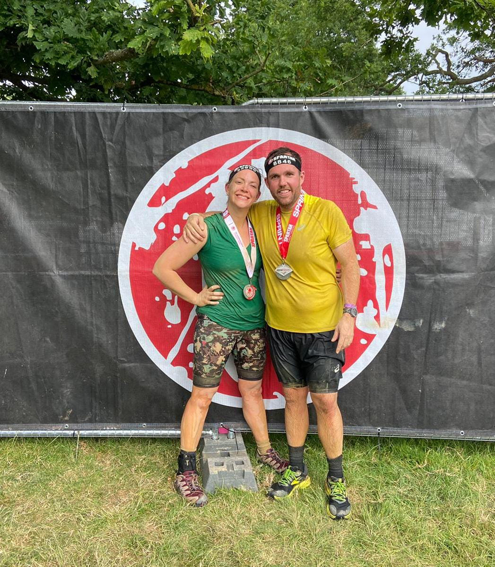 Two people standing in front of a logo celebrating completing the race