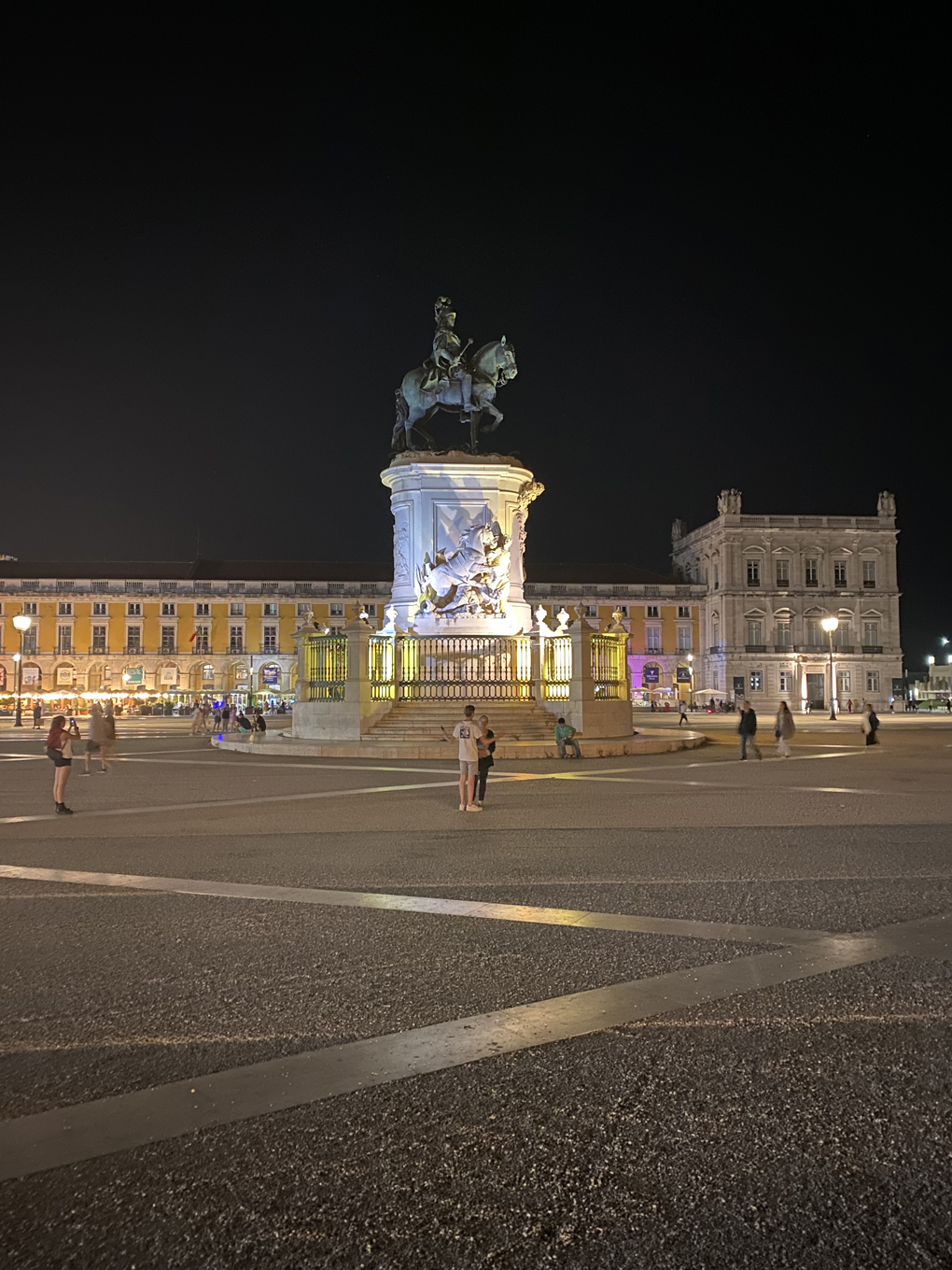 A statue of a man riding a horse is lit up from below with multicoloured lights