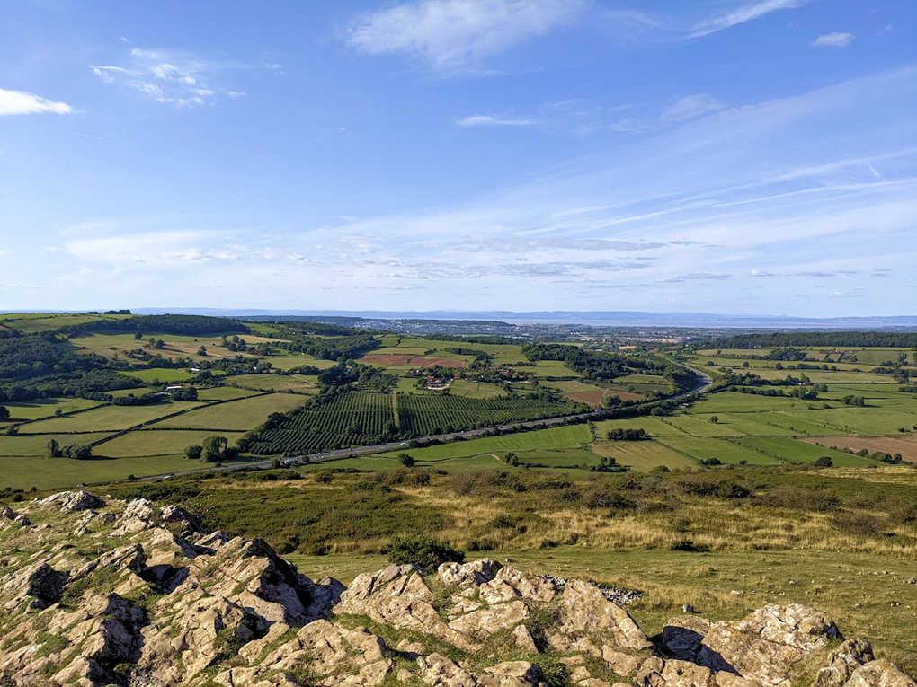 A view of green fields and distant blue horizon under blue skies in southern England