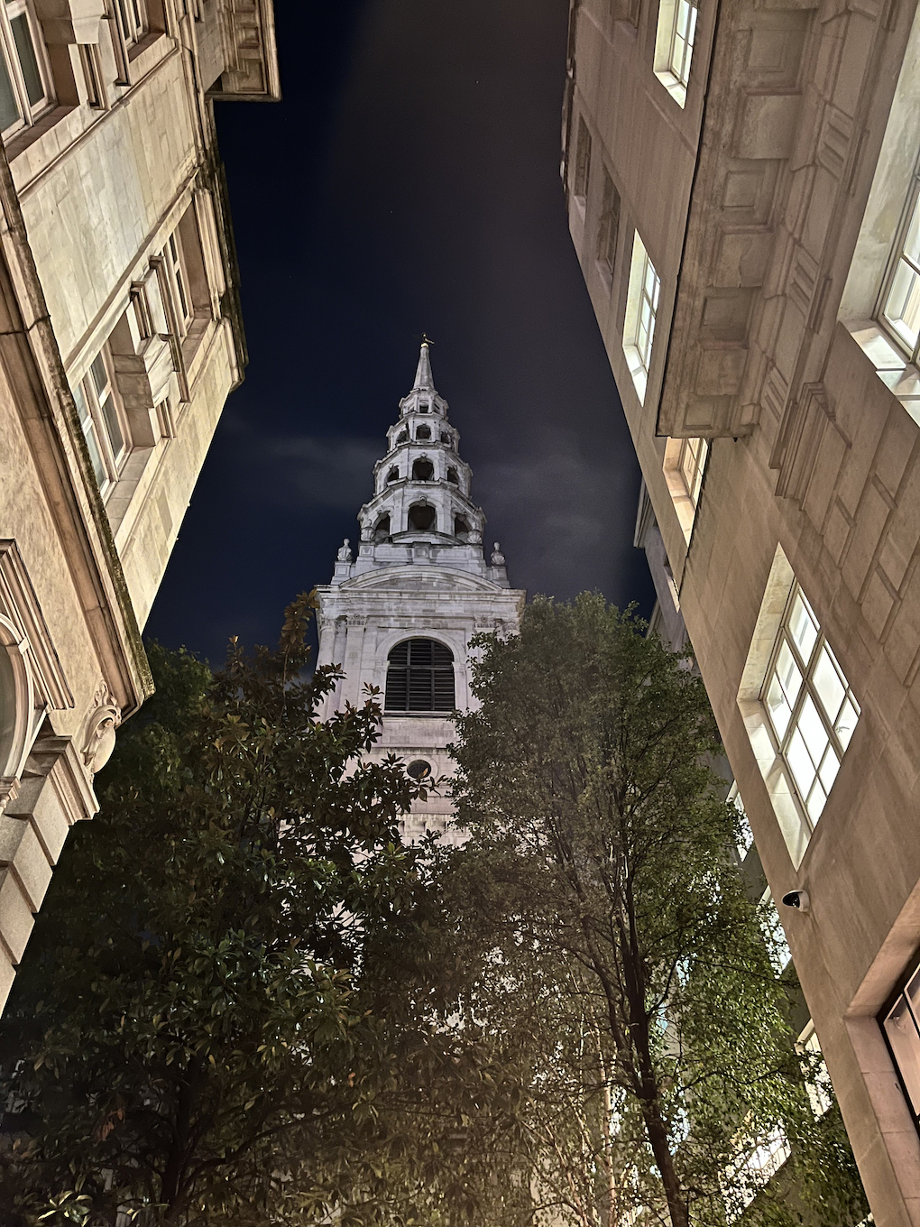 A church spire partially obscured by trees