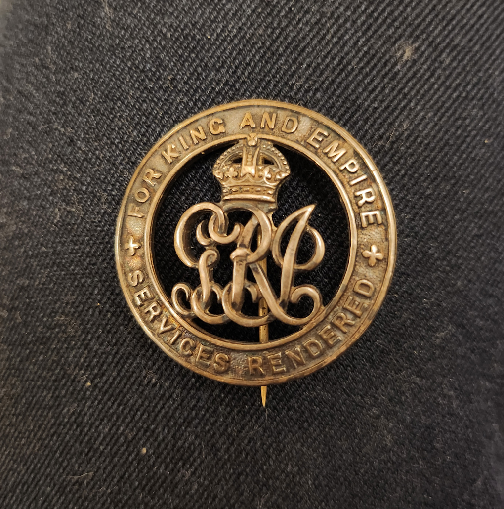 An old round badge. Composed of an outer ring with the words  For King and empire Services rendered emblased around it. The centre is cut out and has the Royal cypher of King George V