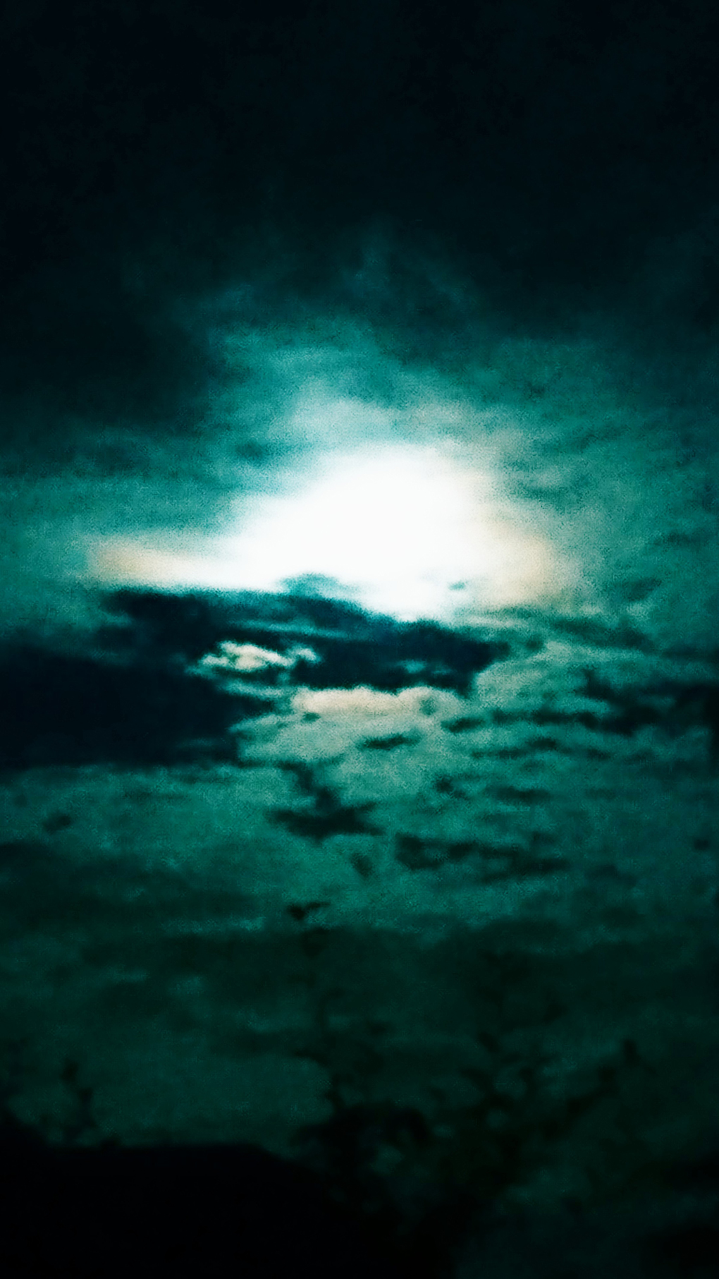 Photo of a bright moon behind strange cloud formation, backlighting them creating a very eerie image. Taken just after Halloween.