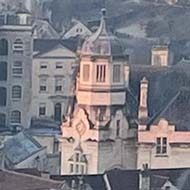 View of many houses on a hillside in Wiltshire. They are tinted pink and gold by the rising sun.