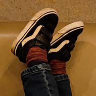 A boy's feet waving in the air at a hotel breakfast table, on which a mirror and razor lay crossed.