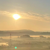 Sun setting over a field and pylons