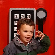 small boy in lego phone box