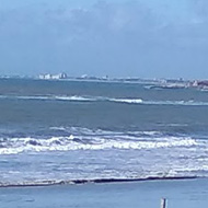 It shows a path through the sand dunes leading down to the sandy beach and blue sea with a blue sky above