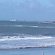 It shows a path through the sand dunes leading down to the sandy beach and blue sea with a blue sky above