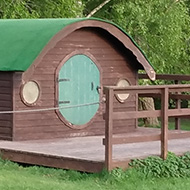 Some small brown huts with round, green doors