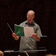 A view from the back of the orchestra showing snare drum and music stands.