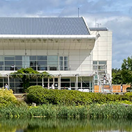 Picture of lake with two storey building in background on a sunny day