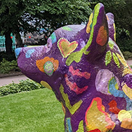 A large brightly painted statue of a corgi in a London garden.