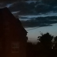 Lit tea light on a windowsill against a twilight sky