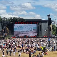 Band playing on stage at an open air festival with large crowd