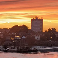 Pink sunset over river with buildings in distance