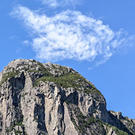 Norwegian fjord giant cliffs descending into still waters pulpit rock overhanging the top two boats at the bottom on a sunny blue sky day