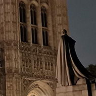 The moon shining behind the Palace of Westminster at night.