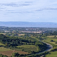 A view of green fields and distant blue horizon under blue skies in southern England