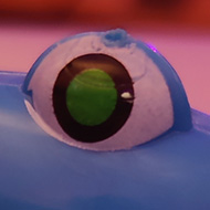 A blue one-eyed alien on a spring on a table in a conference theatre