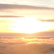 View out the window over an aeroplane wing with a sunset and clouds.