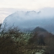 A lovely sleepy river on a very cold and frosty day, reflecting the clouds in a soft blue sky, the distant hills striped with a blanket of fog.