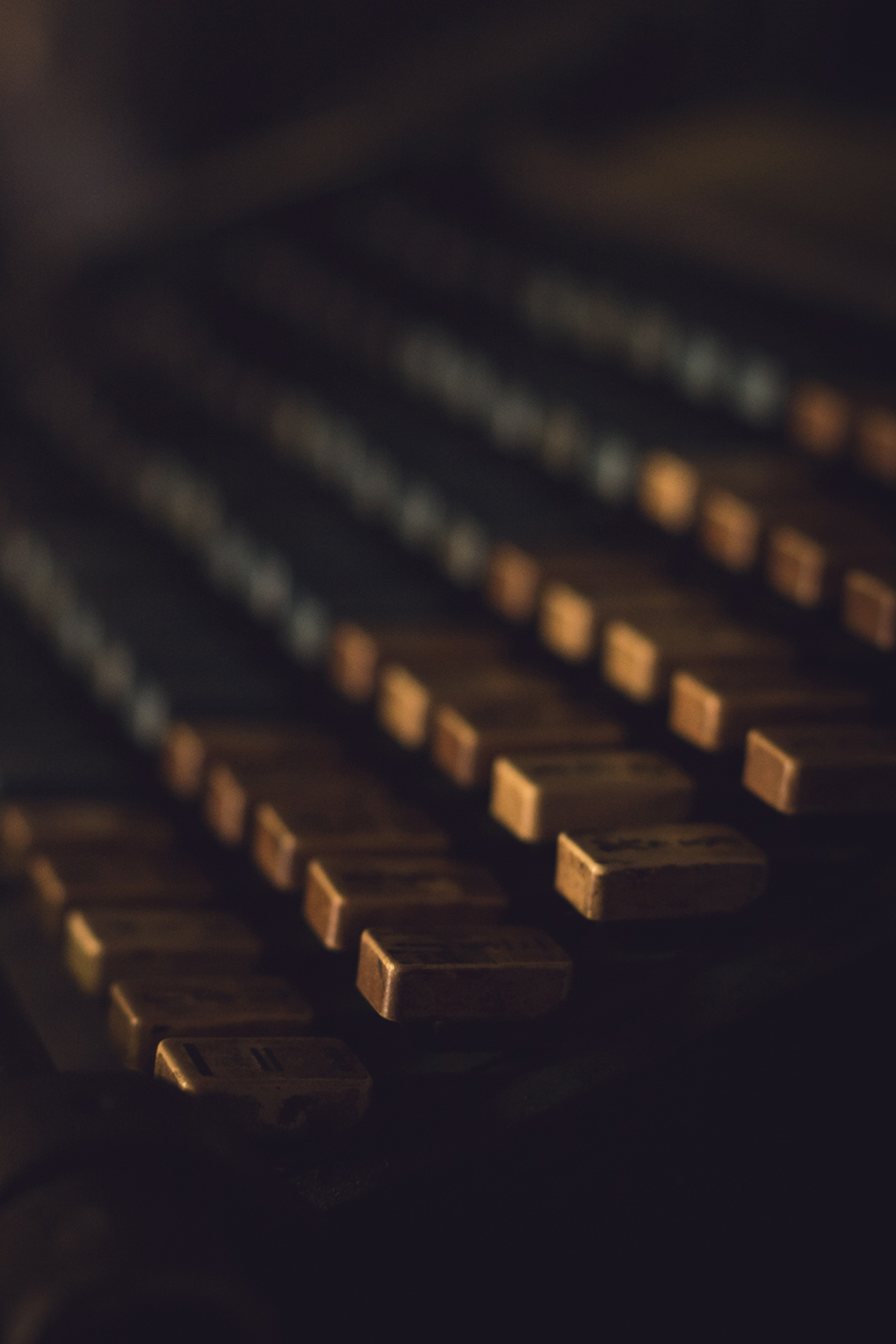 Dusty yellow and blue keys of an old, large, printmakers typewriting machine.