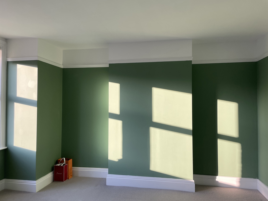Image of plain green wall with sunlight shining on it