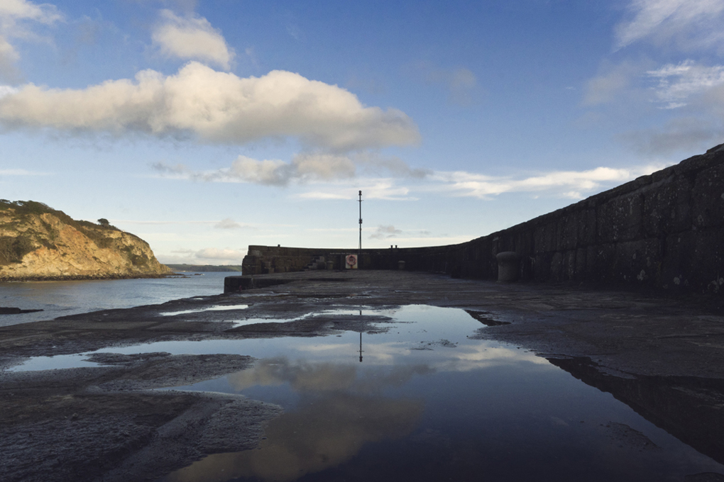 Reflection of a cloudy blue sky on the edge of Charlestown Harbour.