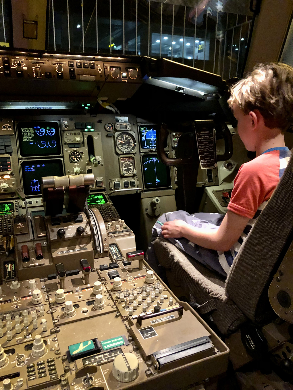 A small boy sat in the co-pilot seat of a aircraft cockpit