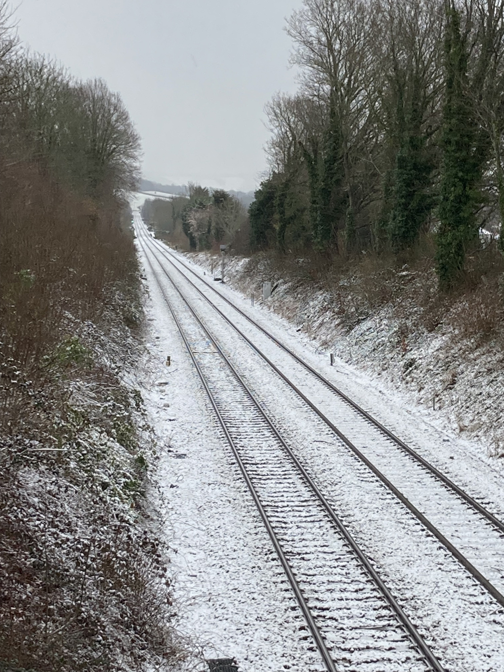 We see a picture of snow on railway tracks emerging from a bridge