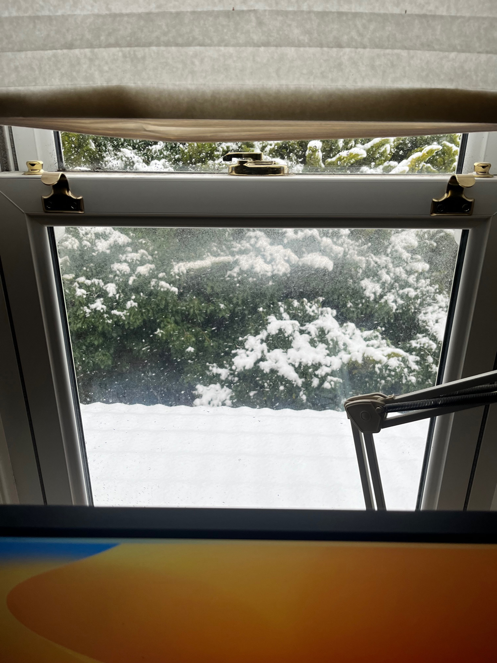 Looking out of a window at a rooftop covered in snow.