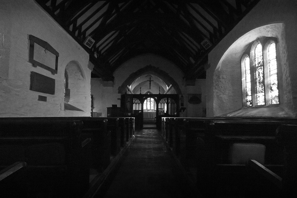 Old stone church with wooden features and light spilling through the side window.