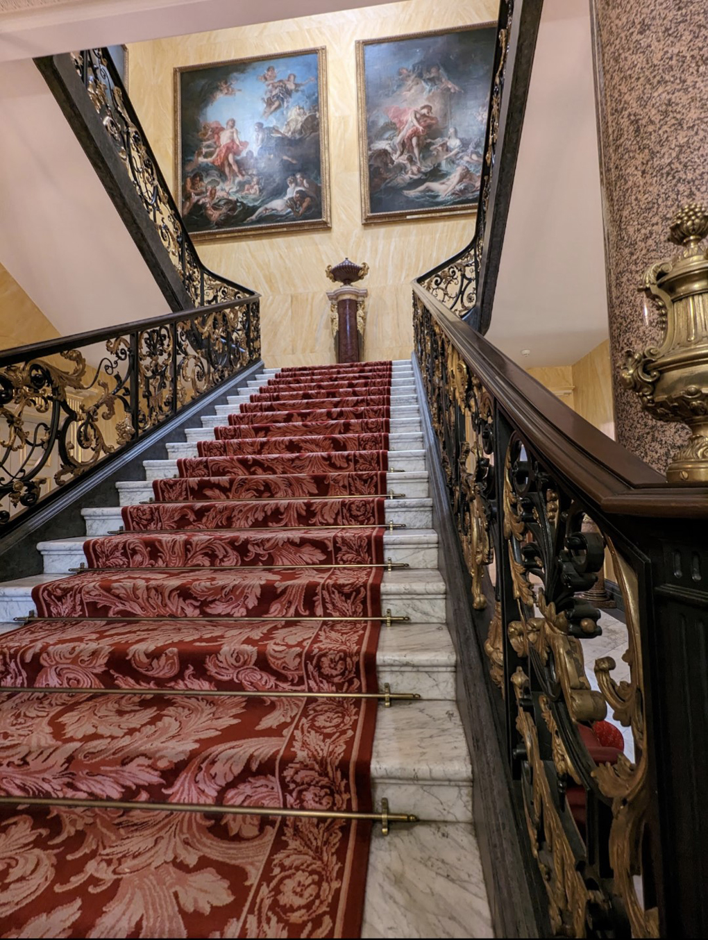 Stairs at the Wallace Museum, carpeted and ornate with two beautiful paintings.