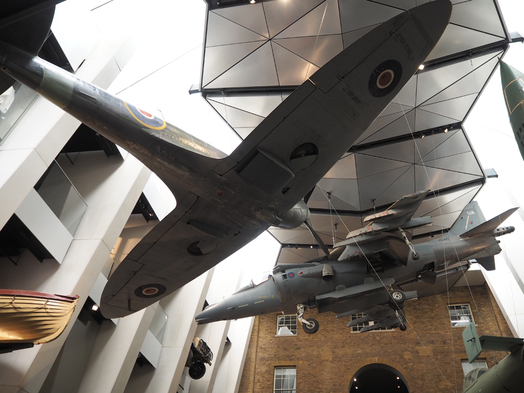 Harrier Jet and Spitfire plane hanging from the ceiling of the IWM looking up to the roof