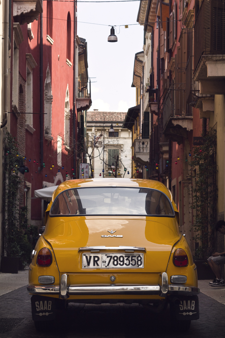 Old mustard yellow car down a narrow Italian side street