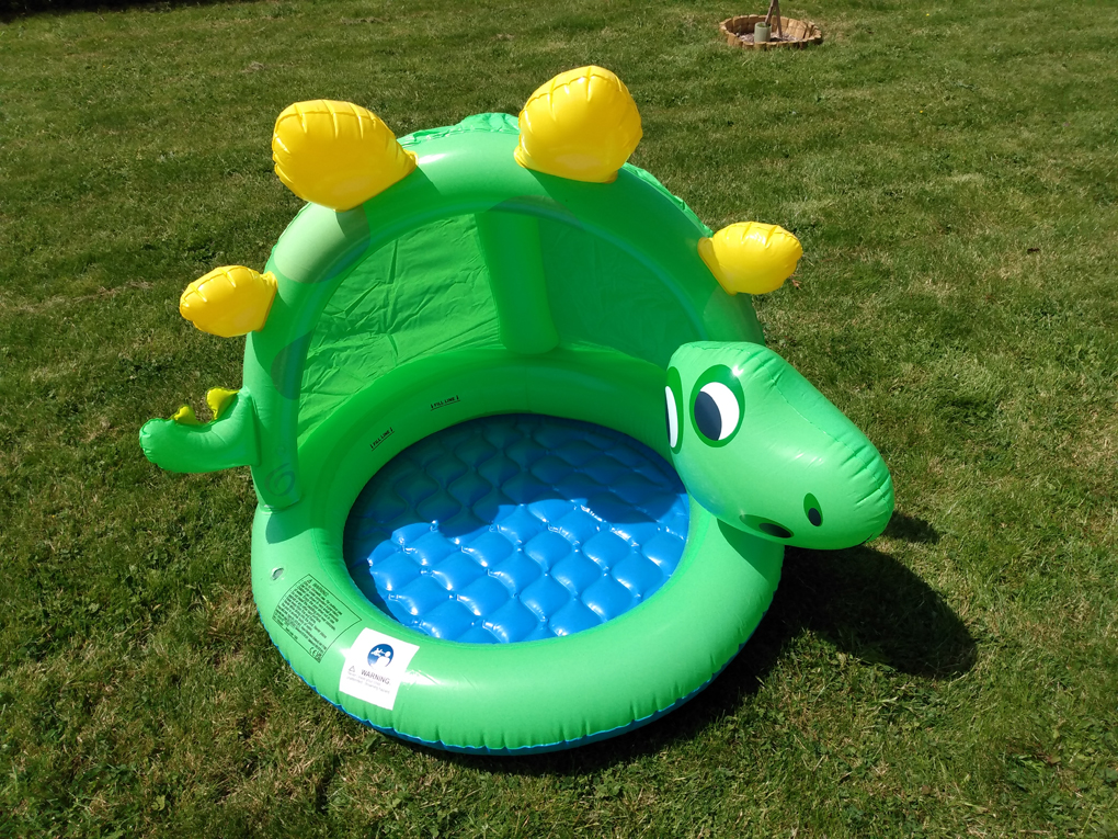 A green, stegosaurus-like paddling pool where the fin becomes a sun shield