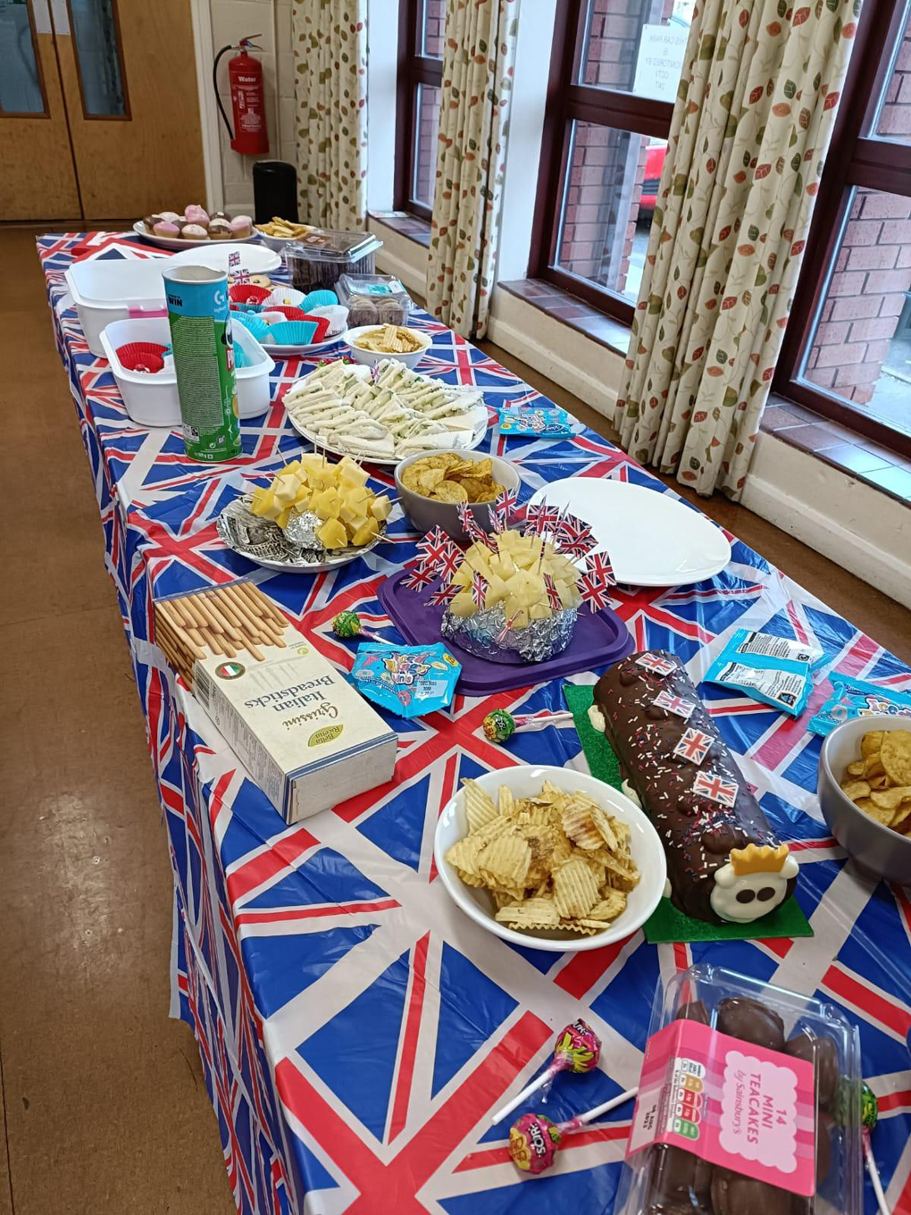 Table covered in coronation-themed food with a Union Jack tablecloth