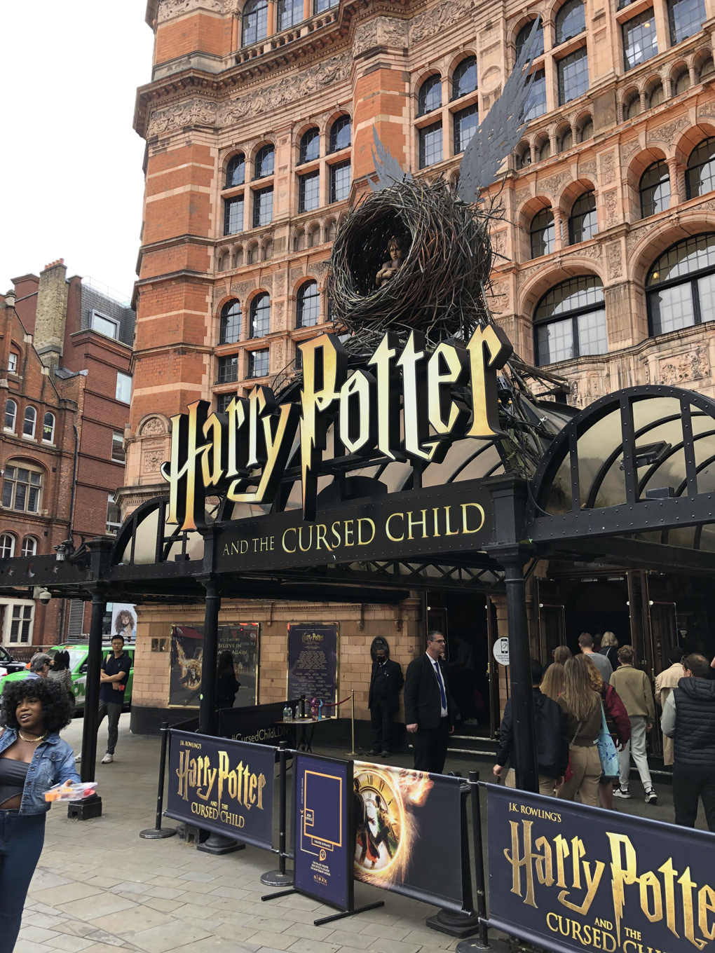 The outside of the Palace Theatre in London, with a crowd standing around under the awning depicting the name of the show