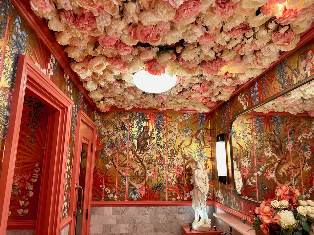 Opulent ladies toilet with jungle print papered walls and fake flowerhead covering the ceiling