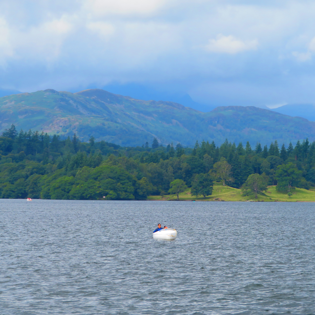 We see a small boat on lake Windemere framed by the mountains