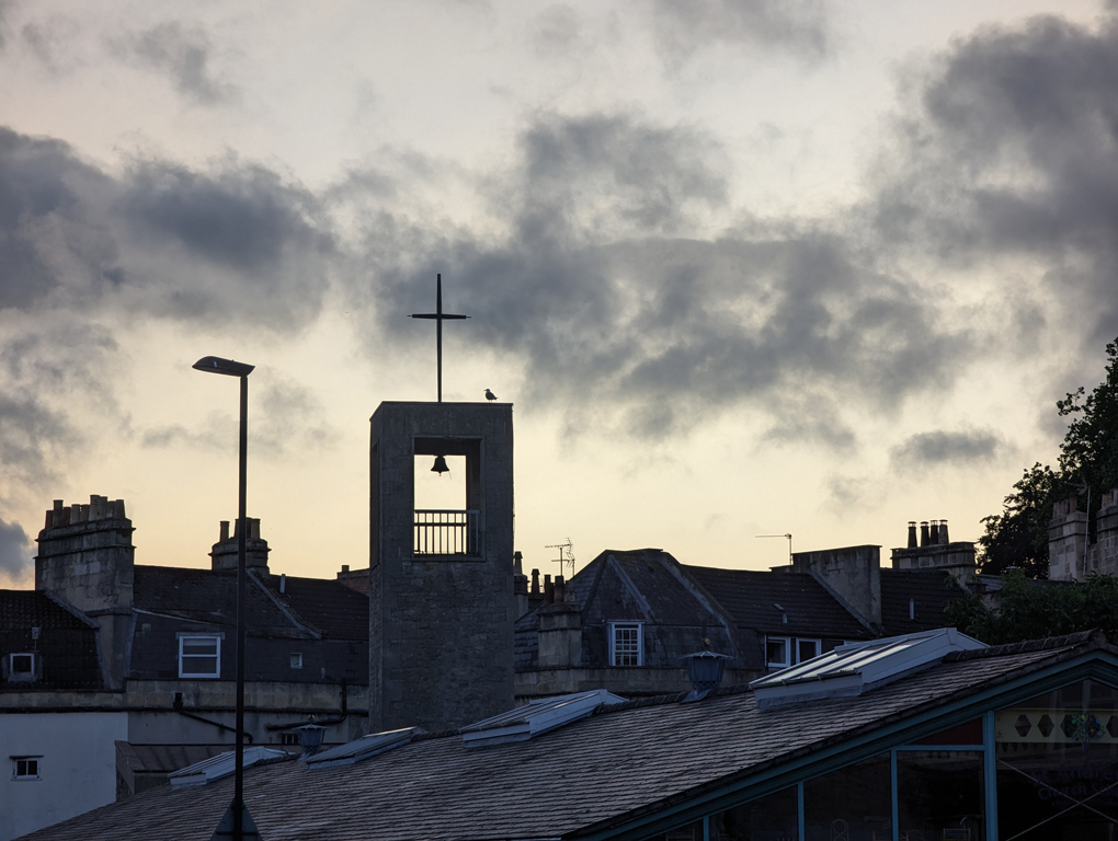 Sun setting over Bath city skyline with a small school bell tower in the foreground.