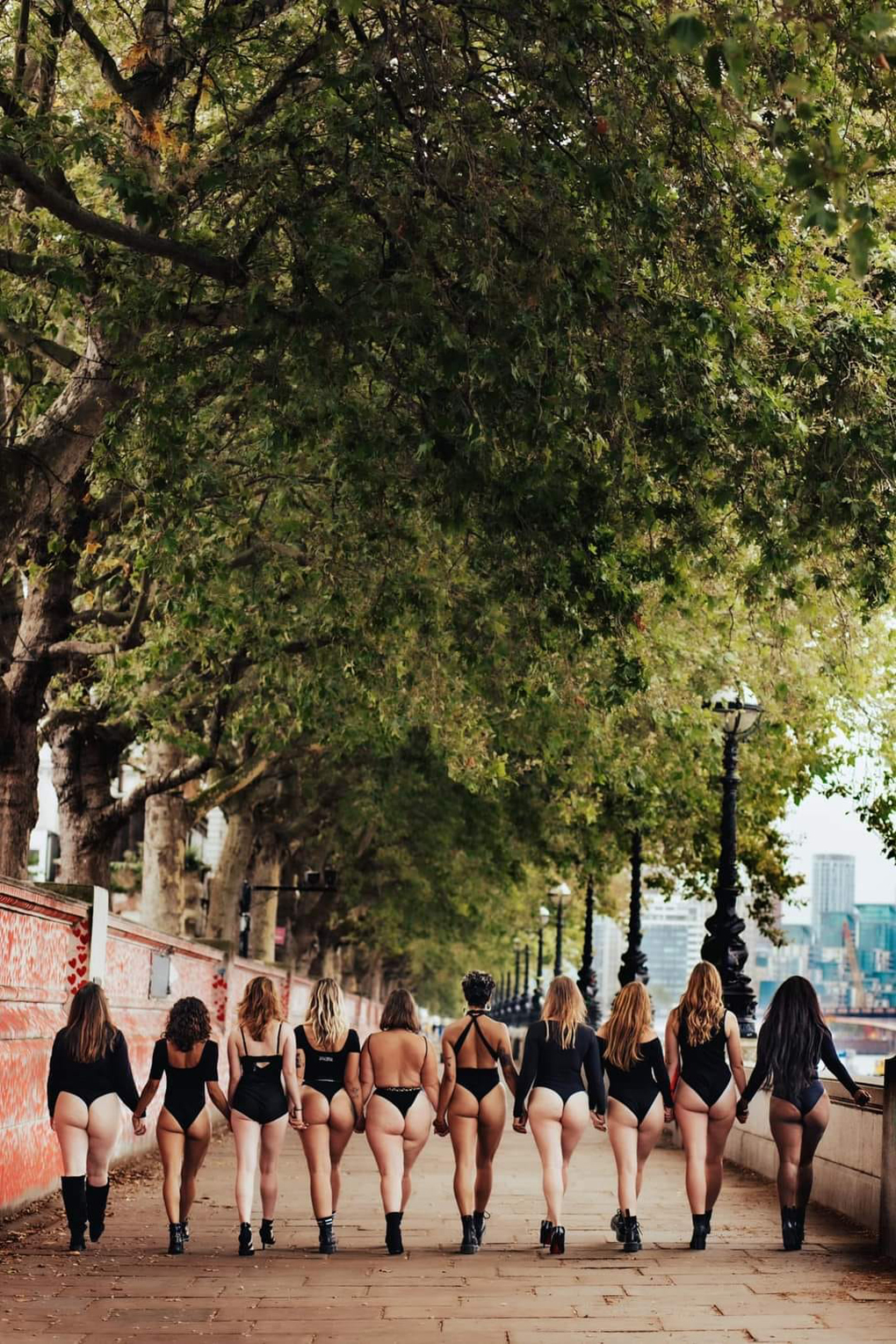 Ten women walking away from the camera in limited attire
