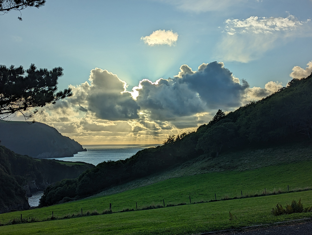 Sunset over Lee Bay with god rays and the sun highlighting the clouds in gold.