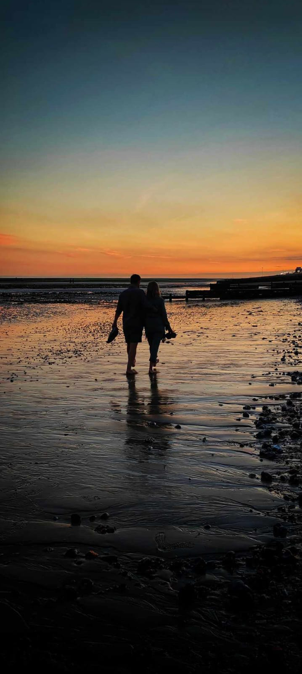 Two people walking on beach in sunset