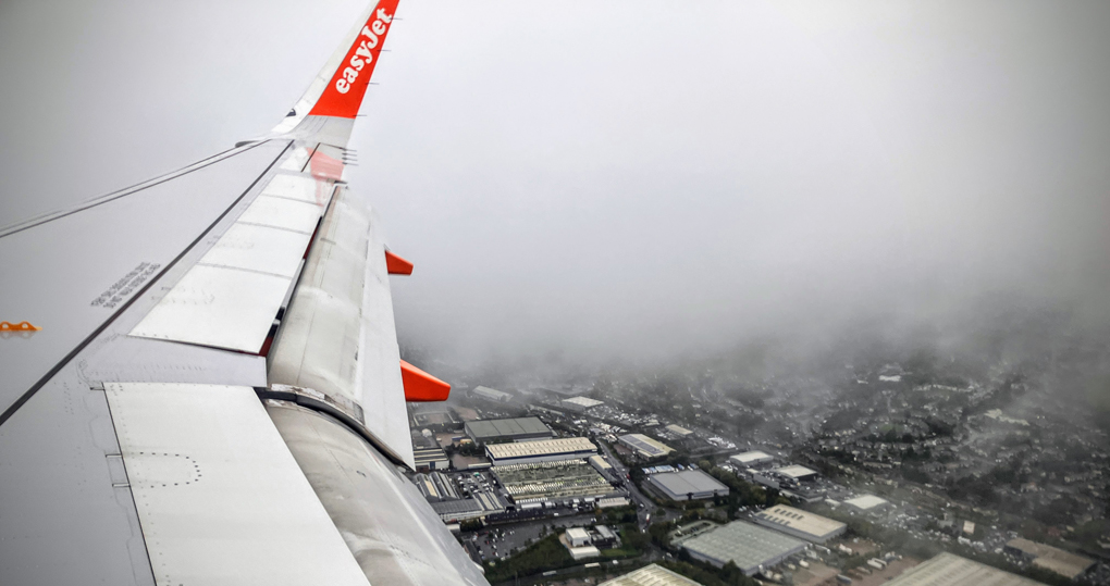 Image of the wing of the easyjet plane with Birmingham factories visible below the clouds.