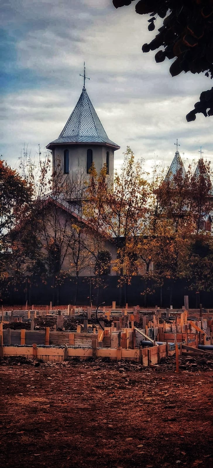 Church behind trees with new building construction in front during Autumn