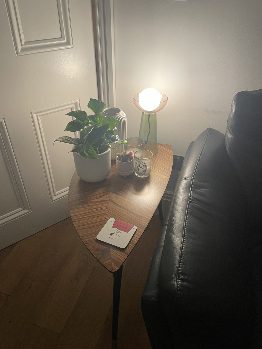 End table with lamp, plant, and candles next to sofa